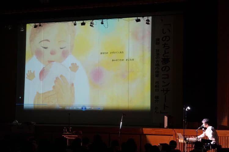スクリーンに映像を映しているコンサートの場面