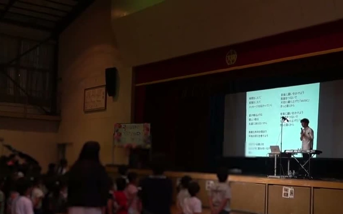 スクリーンに歌詞を映して、子どもたちと一緒に歌う場面